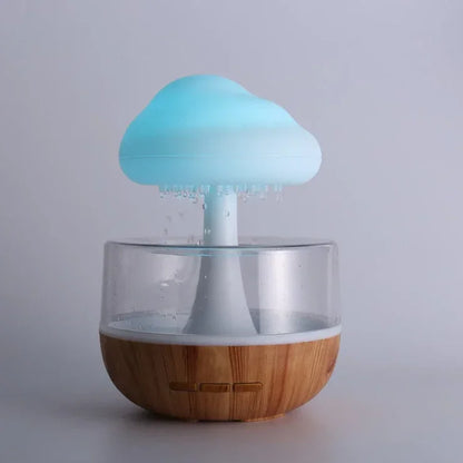Cloud-shaped LED humidifier with wooden base and clear water tank on light background