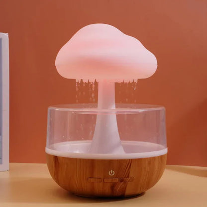 Cloud-shaped LED humidifier with wood base on a beige table, water mist flowing down