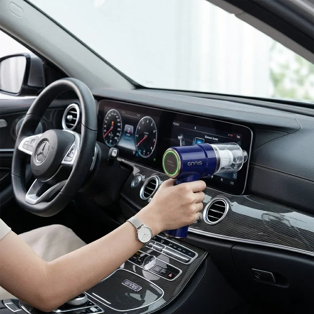 A person using a deep blue handheld car vacuum cleaner to clean the dashboard and screen of a Mercedes-Benz, 9000Pa powerful suction cordless vacuum.