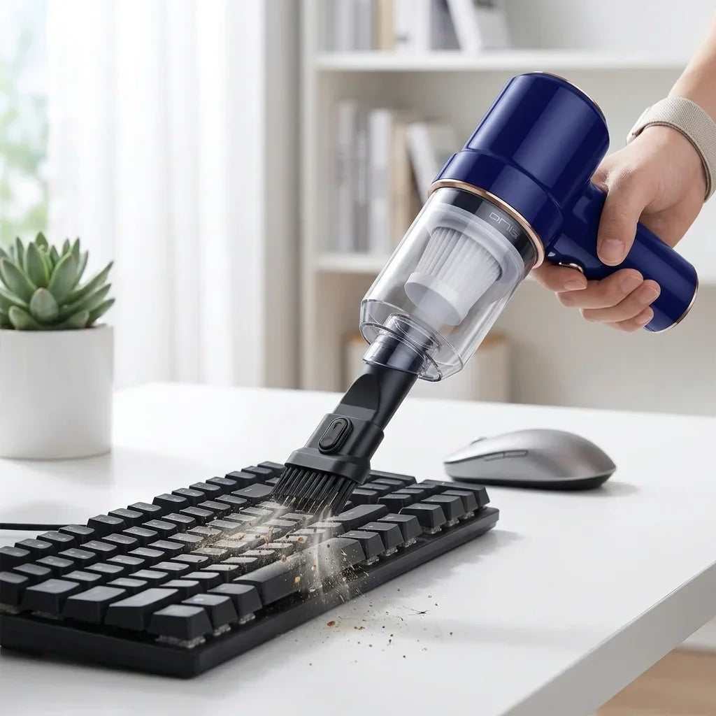 Deep blue portable vacuum cleaner with brush nozzle cleaning a mechanical computer keyboard on a white desk, ideal for home and office use.